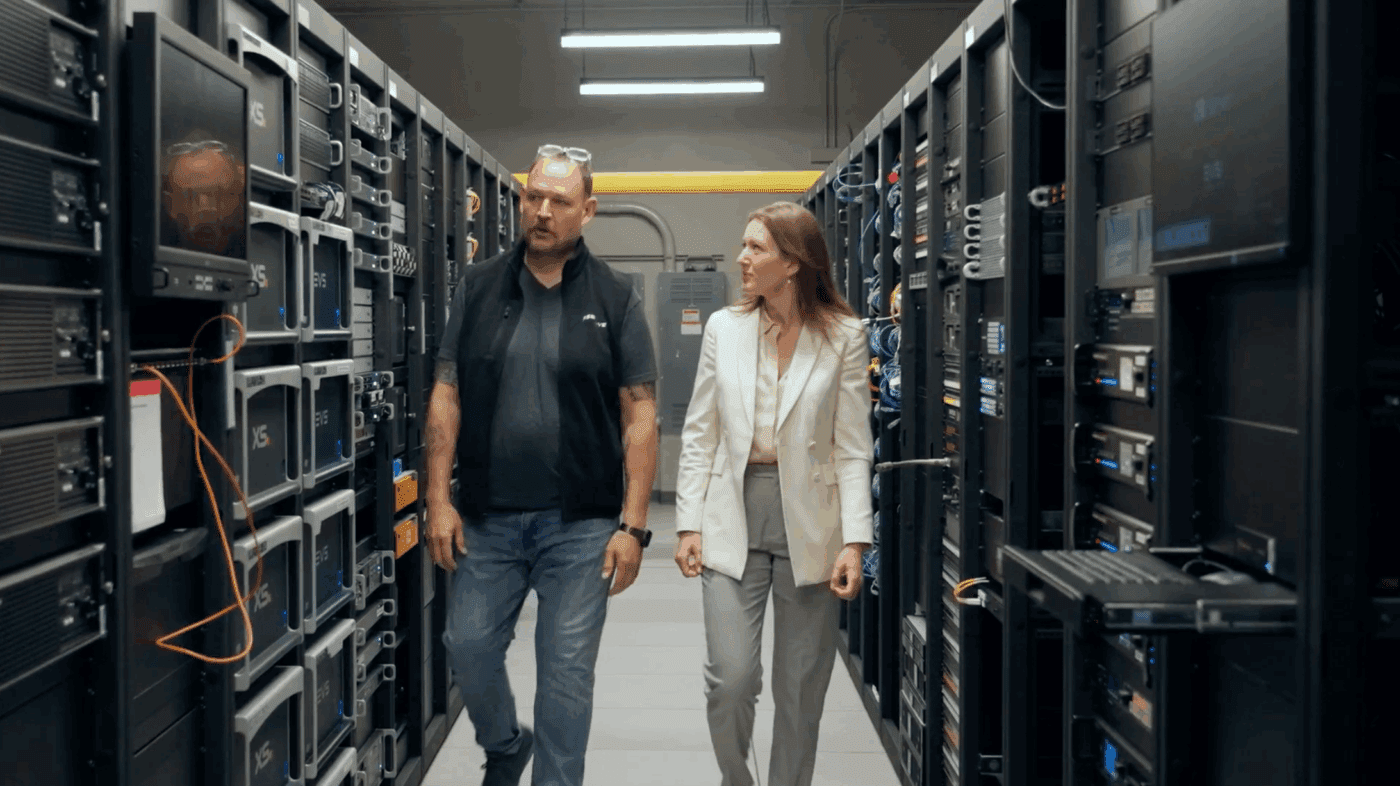 Man and woman walking through racks of hardware for broadcast